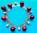 Round Christmas silver tinsel frame with baubles on bright blue background. Royalty Free Stock Photo