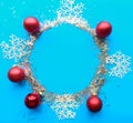 Round Christmas silver tinsel frame with baubles and snowflakes on bright blue background. Royalty Free Stock Photo