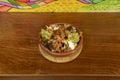 A round clay bowl with nachos with melted cheese, pico de gallo and guacamole