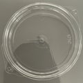 Round, clear plastic lid with a smooth surface and a small central nub. The lid has two Royalty Free Stock Photo