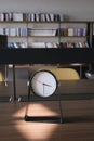 Round clock on table against a library background Royalty Free Stock Photo