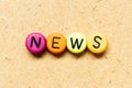 Round bead with black letter in word news on wood background