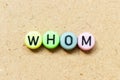 Round bead with black letter in word whom on wood background