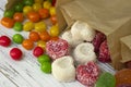 Round colored candy and marmalade in a paper bag on a wooden table, bright sweets, white background