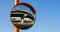 Convex Traffic Mirror Reflecting an Elevated Highway and City Buildings Against a Blue Sky convex mirror Royalty Free Stock Photo