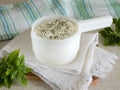 Round cottage cheese in a cheese making mold with dried herbs and fresh basil. Homemade dairy product