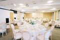 Round covered festive tables with bouquets of flowers stand in a restaurant