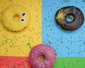 round different donuts with sprinkles on a bright multi-colored background