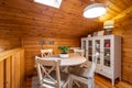 Round dining table with chairs and cupboard in completely wooden house.