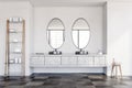 Round double sink in white bathroom, oval mirrors