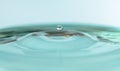 round drop of water over the blue surface of the water