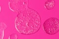 Round drops of white gel with bubbly texture.Jelly texture of antibacterial liquid with bubbles iside.Bright pink background with