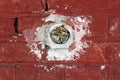 Round electrical outlet box without wires filled with paper mounted inside red brick wall