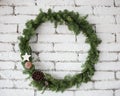 Round elegant Christmas wreath hanging on white brick wall