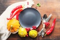 Round empty gray plate with space for text, yellow squash, red hot peppers, viburnum berries and cutlery on an old wooden surface Royalty Free Stock Photo