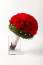 Round, even bridal bouquet of red carnations on a light background