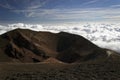 Round extinct crater and silhouettes of mountaineers over clouds at the top of Etna volcano