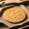 A round flatbread with a golden-brown, slightly textured surface rests on a soft, brown fabric Royalty Free Stock Photo