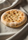 Round flatbread placed on a textured fabric surface. The bread is golden brown with a Royalty Free Stock Photo