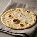 A round flatbread with a slightly uneven surface, featuring golden brown spots, rests on a folded Royalty Free Stock Photo