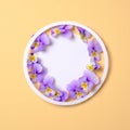 Round floral frame with wild flower petals on pastel yellow background. Top view, tender minimal flat lay style composition. Royalty Free Stock Photo