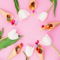 Round frame with bright sugar candy in waffle cones and tulips flowers on pink background. Flat lay, top view Royalty Free Stock Photo