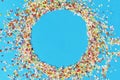 Round frame made of colored confetti. blue background. Festive confetti.