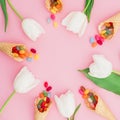 Round frame made of colorful bright candy in waffle cones and tulips flowers on pink background. Flat lay, top view Royalty Free Stock Photo