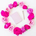 Round frame of pink roses and notebook with pen on white background. Flat lay, top view. Floral pattern Royalty Free Stock Photo