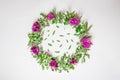 A wreath of violets on a white background. Round frame of purple flowers and fresh grass. Summer flowers. Flat lay, top view.