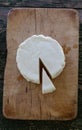 Round fresh cheese with a cut portion. Top view of a cheese on a wooden board Royalty Free Stock Photo