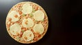 Round frozen pizza. Tomatoes, mozzarella, pesto, basil. Anthracite background.