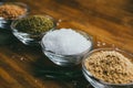 Round glass spice bowl on a wooden table - ground ginger, hops-suneli and sea salt