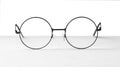 Round glasses with metal frame on table against white background Royalty Free Stock Photo