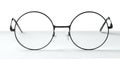 Round glasses with metal frame on table against white Royalty Free Stock Photo