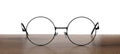 Round glasses with metal frame on wooden table against white background Royalty Free Stock Photo