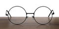 Round glasses with metal frame on wooden table against white background Royalty Free Stock Photo