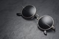 Round gray metal sunglasses on on black slate background
