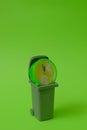 A round green clock showing 5 minutes before 12 in a trash can on a bright green background. Text space. Environmental protection. Royalty Free Stock Photo