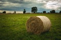 Round hay bale in a green meadow and cloudy sky Royalty Free Stock Photo