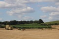 Round hay bales in a field in the British countryside being harvested by tractor on to a truck Wakefiel, West Yorkshire UK Royalty Free Stock Photo