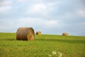 Round hay bales in a field of green grass with blue sky and clouds Royalty Free Stock Photo