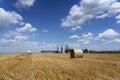 Hay Bales and Grain Silos in a Field Against Blue Sky With White Clouds Royalty Free Stock Photo