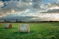 Round hay bales lying on a meadow, clouds and sunshine on the sky Royalty Free Stock Photo