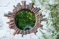 A round hole in a brick wall in a park looks like a portal