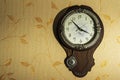 Round home brown wall Clock with a pendulum on a light wall