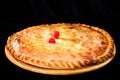 round homemade delicious cherry pie on wooden board, dark background Royalty Free Stock Photo