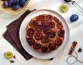 Round honey cake or muffin with fresh plums on a light grater on a light concrete background. Plum baked goods Royalty Free Stock Photo