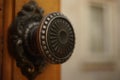 Round iron handle with a pattern on an old wooden door, closeup. Background in blur of a building with a window Royalty Free Stock Photo