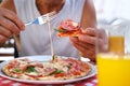 round italian pizza cut into slices on table, male hands take pieces of pizza with salami, cheese, arugula, hands with food close- Royalty Free Stock Photo